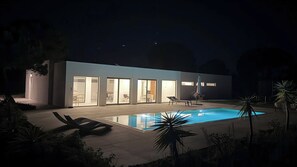 A modern house with a swimming pool, large glass doors, and outdoor furniture.