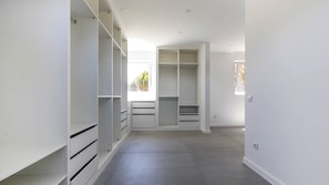A spacious walk-in closet with multiple shelves and drawers, a large window with a view of greenery, and a clean, modern interior. - Quinta do Vale- Oasis Vila  (Sesimbra)