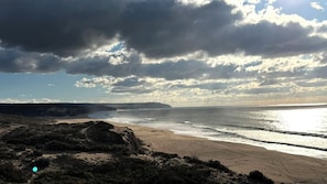 A coastal landscape with a beach, rocky terrain, and a distant cliff. - Quinta do Vale- Oasis Vila  (Sesimbra)