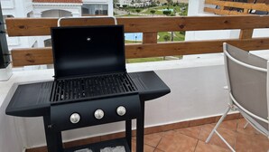 Un balcone con ringhiera nera, pareti bianche e vista sulla spiaggia e sugli edifici.