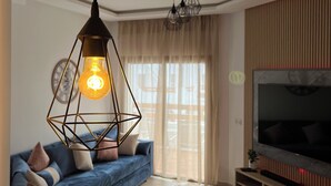 Un soggiorno moderno con un divano blu, un tavolino da caffè e una TV su un mobile in legno.