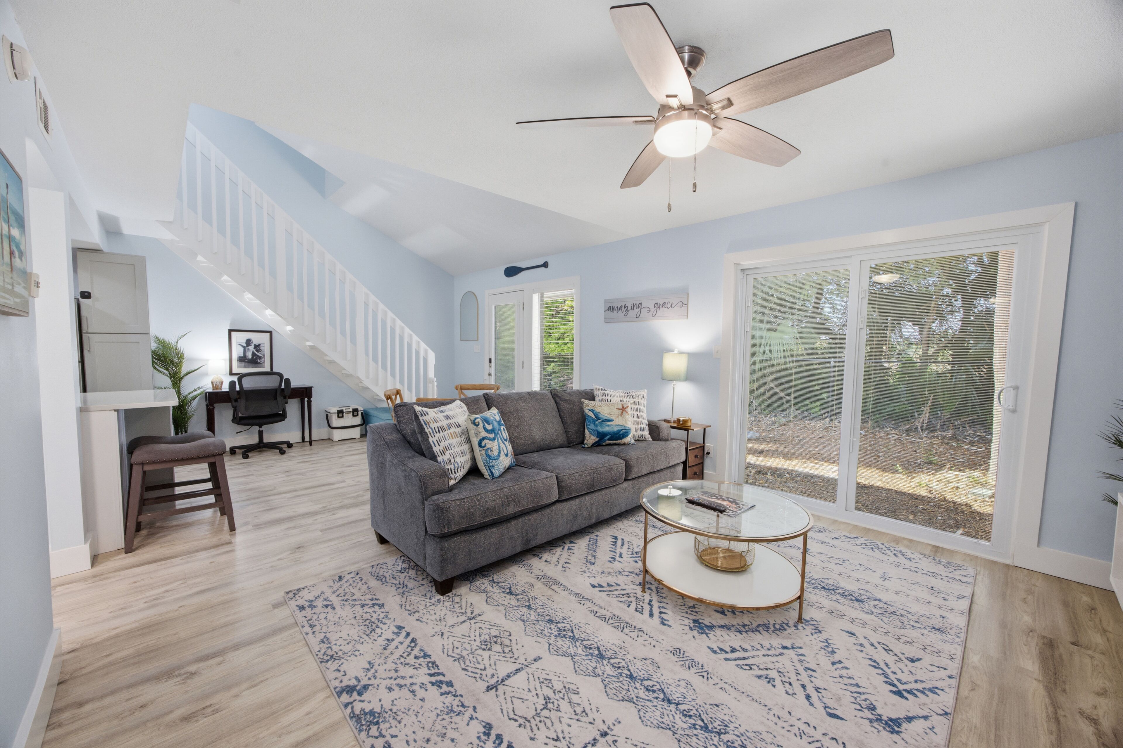 A spacious living room with a grey sofa, a coffee table, and a ceiling fan.