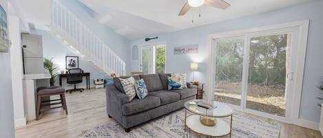 A spacious living room with a grey sofa, a coffee table, and a ceiling fan.