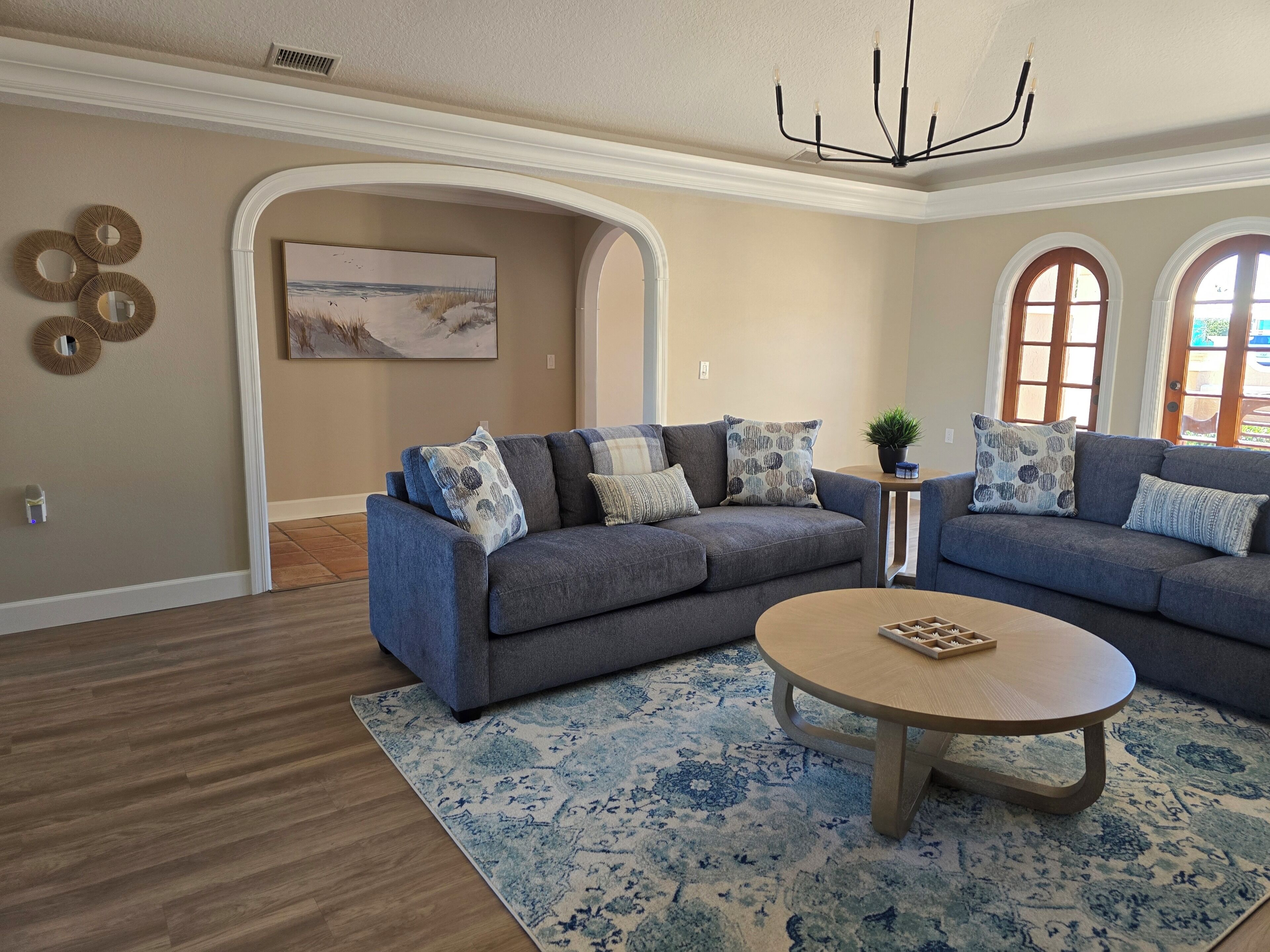 A living room with a grey sofa, a round coffee table, and a patterned rug.