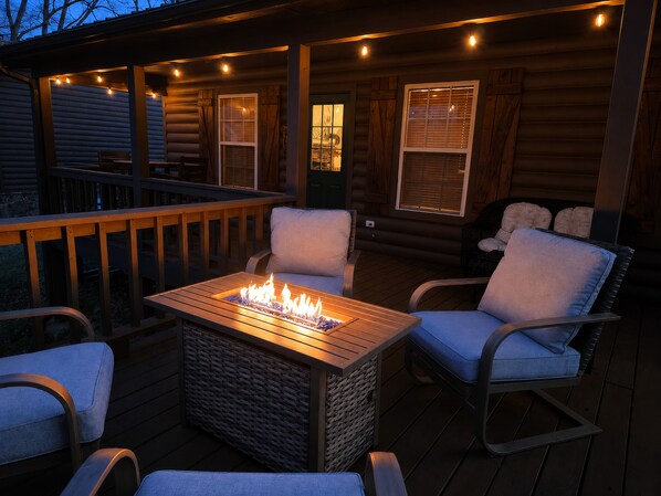 A deck with a fire pit, chairs, and a view of the house.