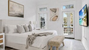 Ein Schlafzimmer mit einem Bett, einem Nachttisch, einem Fernseher, einem Fenster und einer Tür, die auf einen Balkon führt.