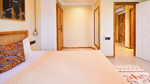 A hotel room with a bed, a painting on the wall, an air conditioning unit, and a hallway leading to another room. - Castle Residence by Aura  (Jambiani)