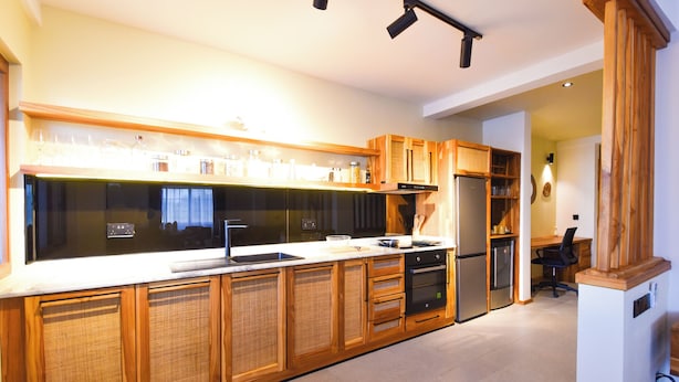 A modern kitchen with wooden cabinets, a stainless steel refrigerator, and a built-in oven. - Castle Residence by Aura  (Jambiani)