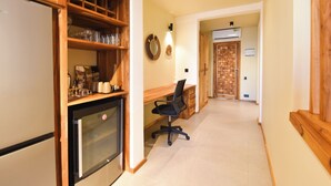 A kitchen with a refrigerator, oven, and wooden shelves. There is a desk with a chair and a wall-mounted mirror. A door leads to another room. - Castle Residence by Aura  (Jambiani)