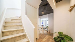 A staircase leading to a living area with a wooden floor, white walls, and a ceiling with exposed beams.