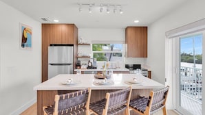 Een moderne keuken met een centraal eiland, houten kastjes en uitzicht op de jachthaven door grote ramen.
