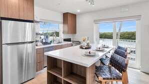Een moderne keuken met een roestvrijstalen koelkast, houten kasten en een groot eiland met zitplaatsen.