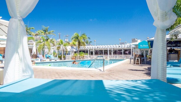 A pool area with a clear blue sky, palm trees, and a covered seating area. - Waterfront Retreat with Marina Views & Pool (Marathon)