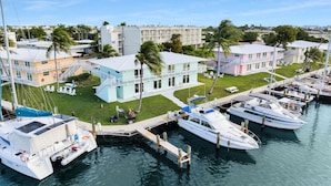 A marina with several boats docked, a light blue building with a balcony, and a pink building with a staircase. - Waterfront Retreat with Marina Views & Pool (Marathon)