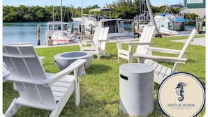 A marina with white lounge chairs and a trash can, boats docked, and a building labeled "Ocean View Marina". - Waterfront Retreat with Marina Views & Pool (Marathon)