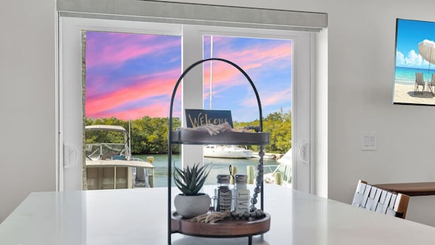A dining area with a view of boats and a sunset. - Waterfront Escape with Pool, Tiki, Breakfast & Marina (Marathon)