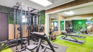 Et fitnesscenter med forskellig træningsudstyr, herunder en squat-stativ, bænkpres og konditionsmaskiner.