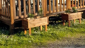 Ein Mobilheim mit Holzterrasse, mehreren Fenstern und einem kleinen Garten mit Pflanzen.