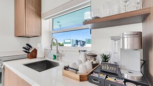 A modern kitchen with a large window, a coffee maker, and a welcome sign. - Boot Key Harbor Retreat with Pool & Breakfast (Marathon)