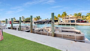 A marina with boats docked, a grassy area, and a building with palm trees in the background. - Boot Key Harbor Retreat with Pool & Breakfast (Marathon)