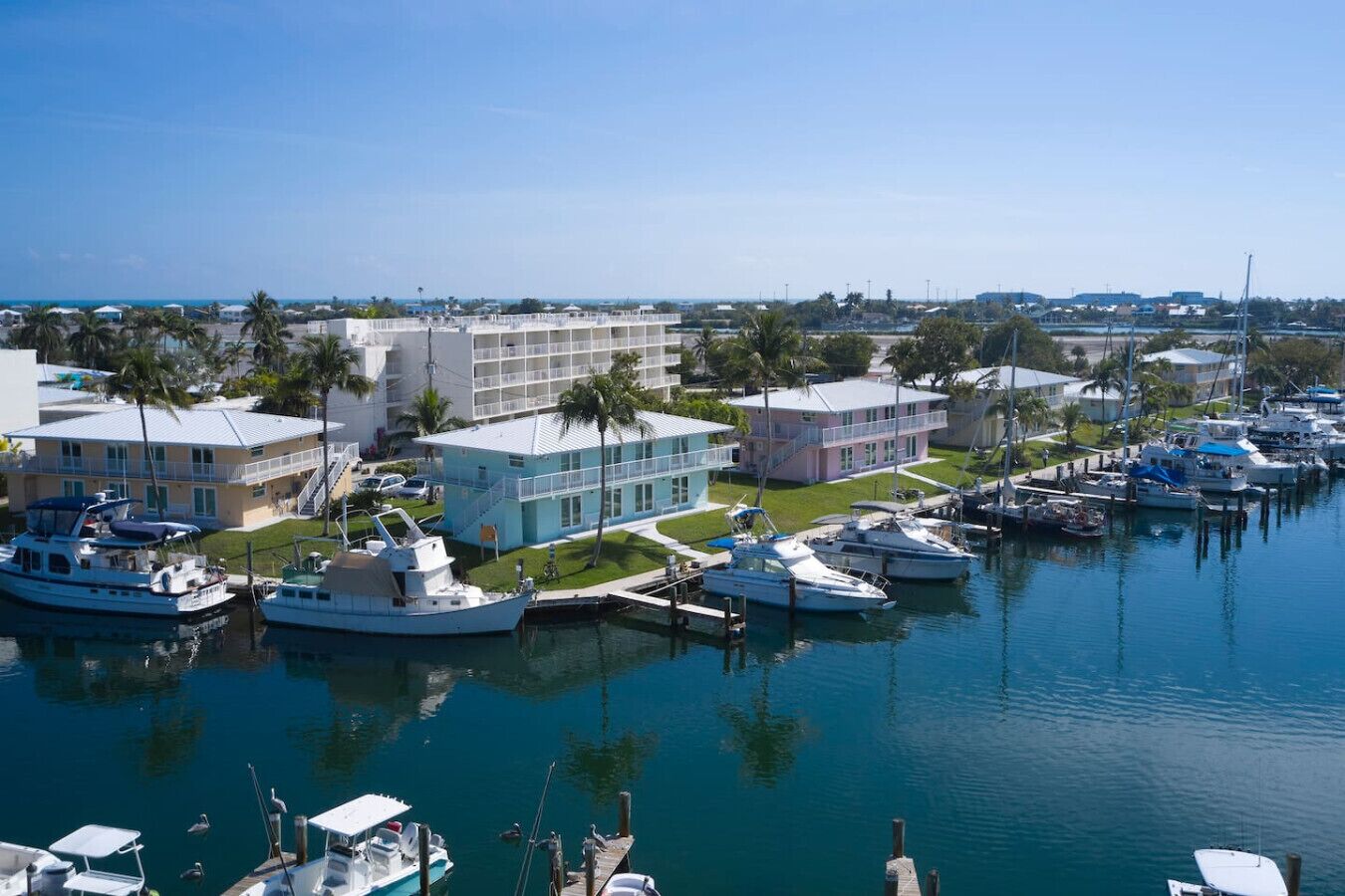 A marina with several boats docked, a building with a balcony, and a clear view of the water.