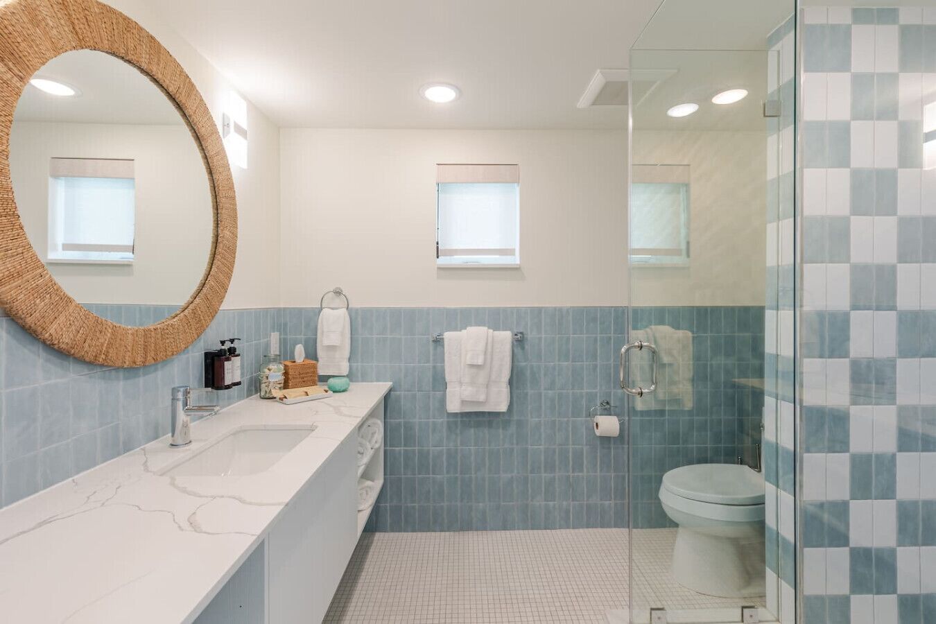 A modern bathroom with a marble sink, a large mirror, and a glass shower enclosure.