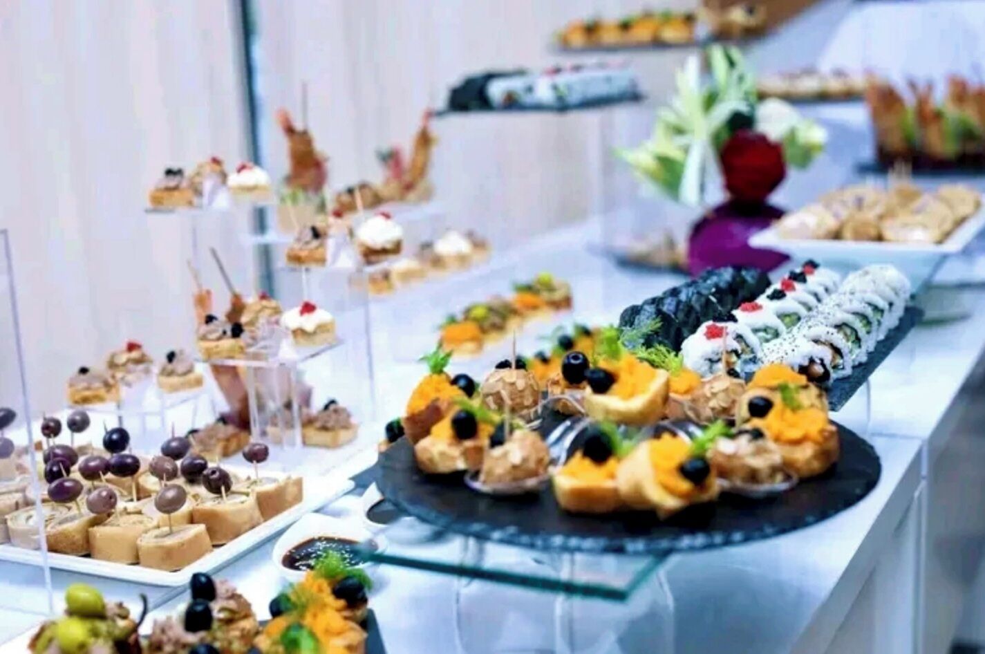 Un bufé con diversos postres y aperitivos, incluyendo pasteles, frutas y otras delicias dulces.