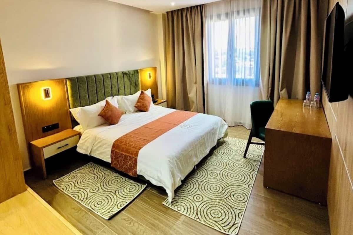 A modern hotel room with a large bed, a desk, and a TV.