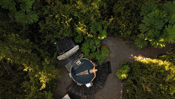 Vista aérea de un espacio de estar al aire libre circular, con una mesa central y bancos, rodeado de abundante follaje.