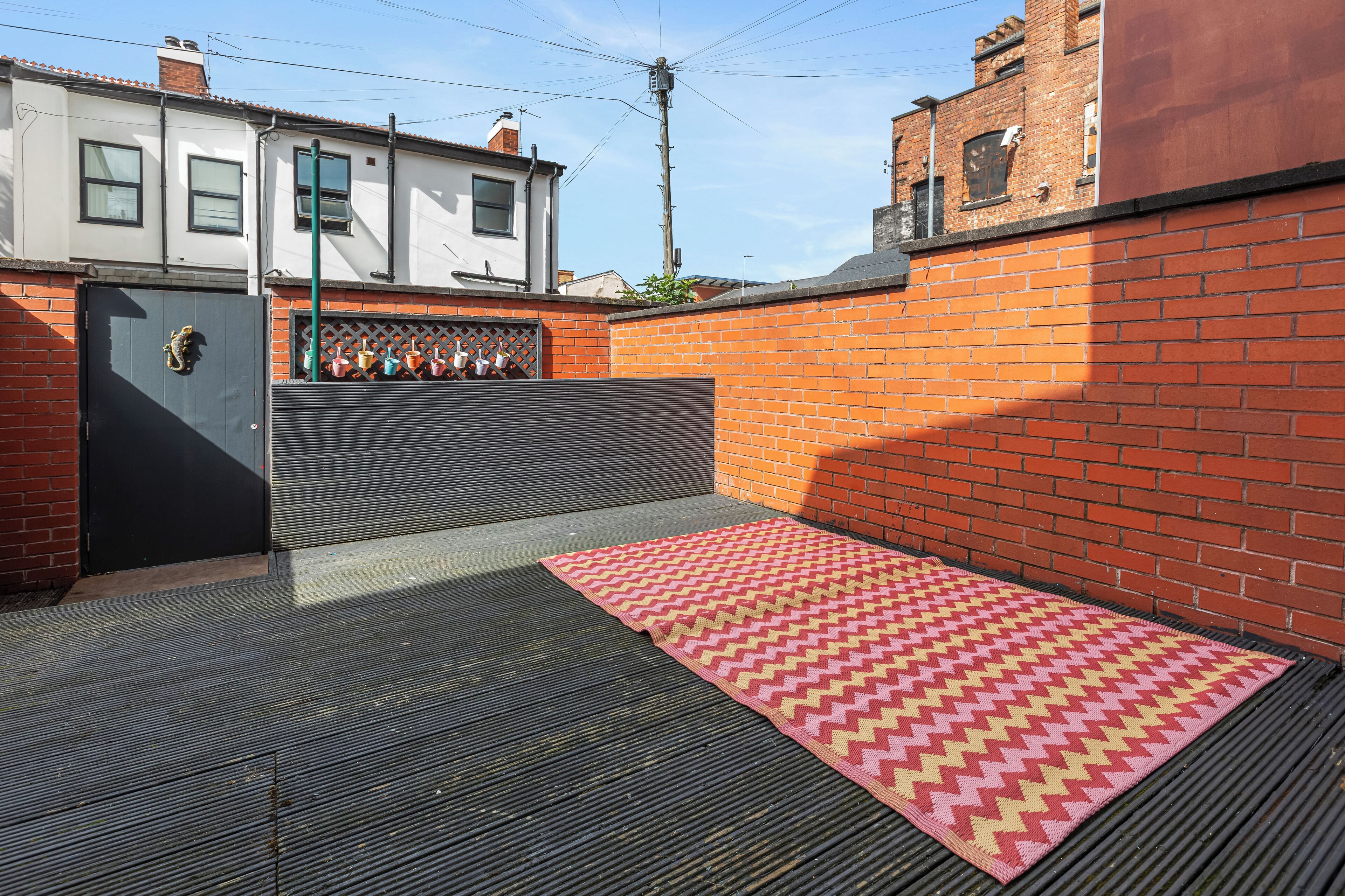 A courtyard with a patterned rug, a metal gate, and a brick wall.