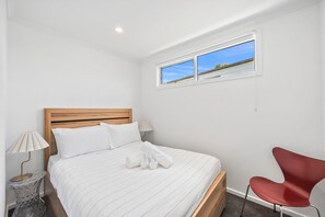 A bedroom with a bed, a window, a chair, and a lamp.