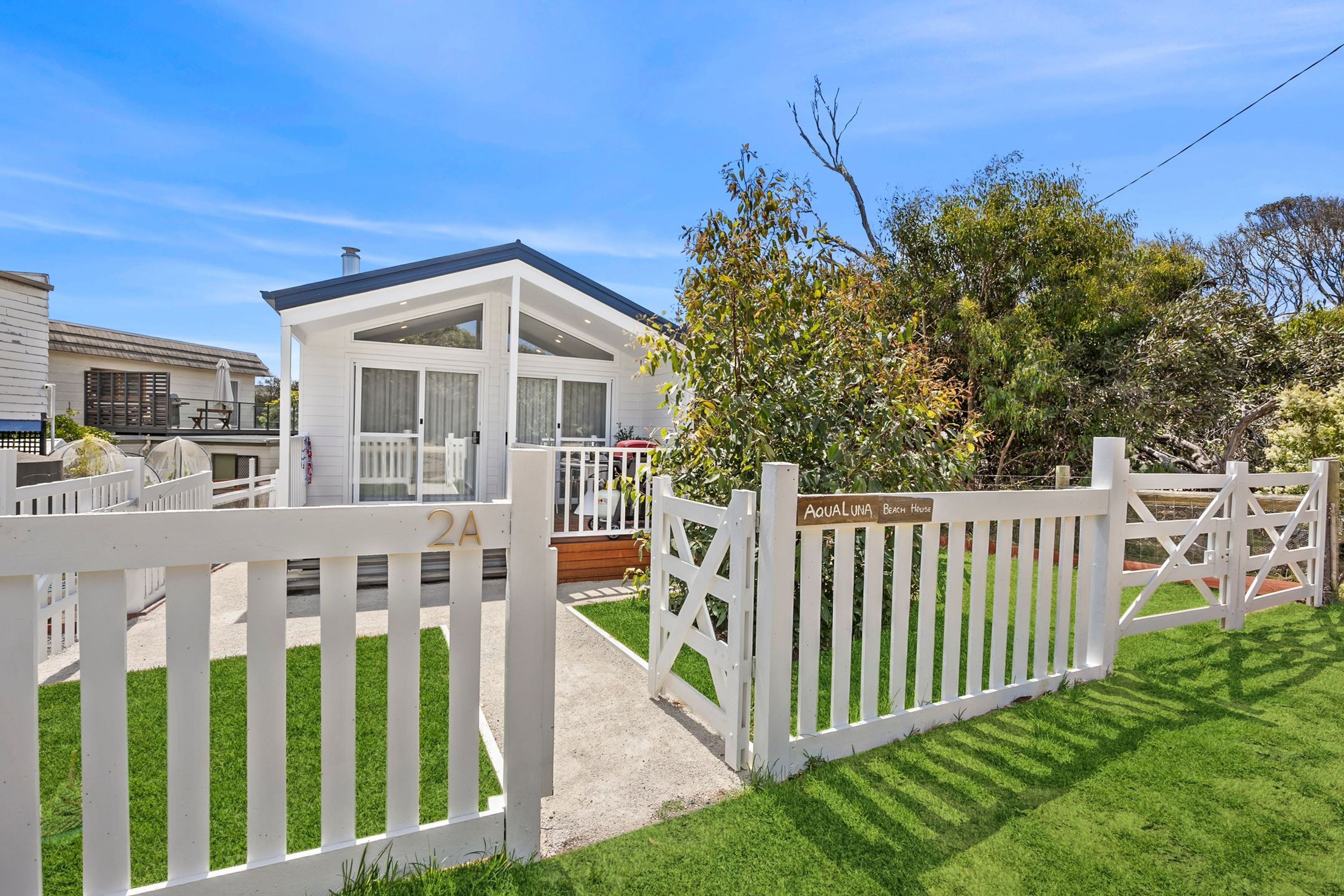 A modern house with a white exterior, a covered porch, and a fenced yard.