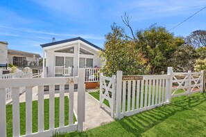 A modern house with a white exterior, a covered porch, and a fenced yard. - AquaLuna Beach House (Aireys Inlet)