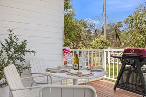 A deck with a table set for two, a grill, and a chair. - AquaLuna Beach House (Aireys Inlet)