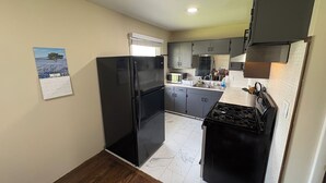 Una cocina compacta con refrigerador, estufa, microondas y gabinetes.