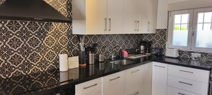 A kitchen with patterned backsplash, white cabinets, and a black countertop. - Sea view-Town-House-Comfort-Private Bathroom (Nerja)