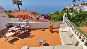A terrace with a table and chairs, a potted plant, and a view of the sea. - Sea view-Town-House-Comfort-Private Bathroom (Nerja)