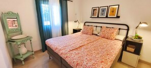 A bedroom with a bed, a nightstand, a bedside table, a mirror, and a window with curtains. - Sea view-Town-House-Comfort-Private Bathroom (Nerja)