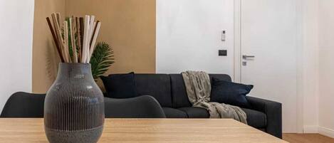 A modern living room with a dark sofa, a wooden coffee table, and a vase with sticks.
