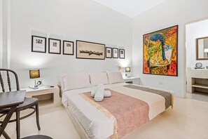 A bedroom with a bed, a desk, a chair, and a large painting on the wall. - Luxury 4 BR House Inside The Walled City With Maid And Staff (cartagena)