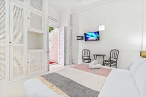 Ein Hotelzimmer mit Bett, Fernseher, zwei Stühlen und einem geöffneten Kleiderschrank.