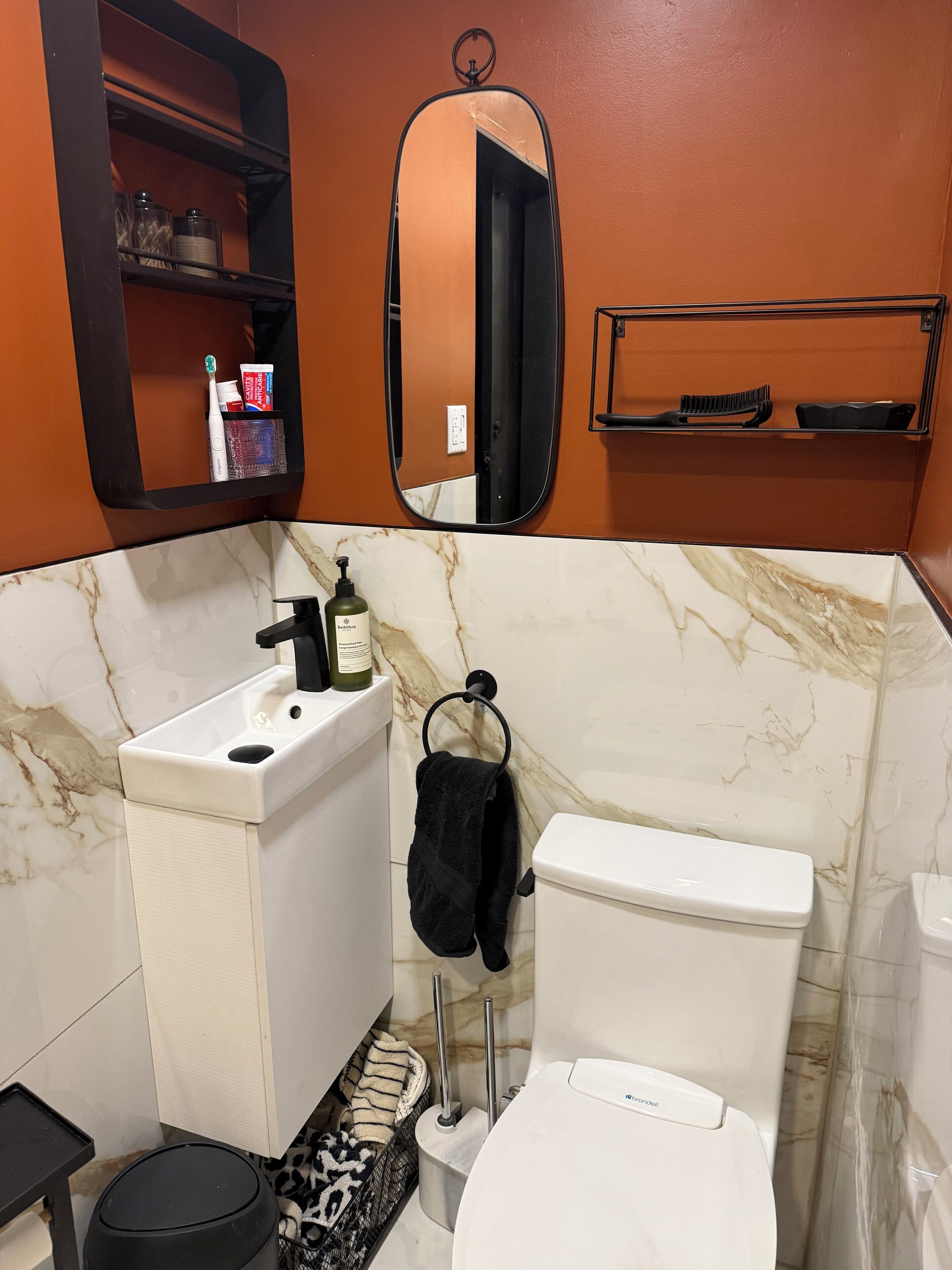 Een badkamer met een wit wastafel, toilet, spiegel en een plank met toiletartikelen.