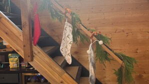 Una escalera de madera adornada con decoraciones navideñas, incluyendo calcetines y una guirnalda.