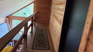 Un interior de madera con un balcón, un tapete y una puerta.
