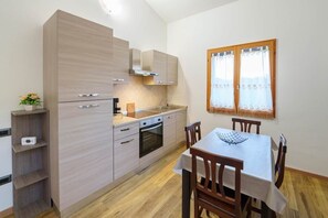 Una cocina moderna con armarios de madera, horno empotrado y una mesa de comedor con sillas.
