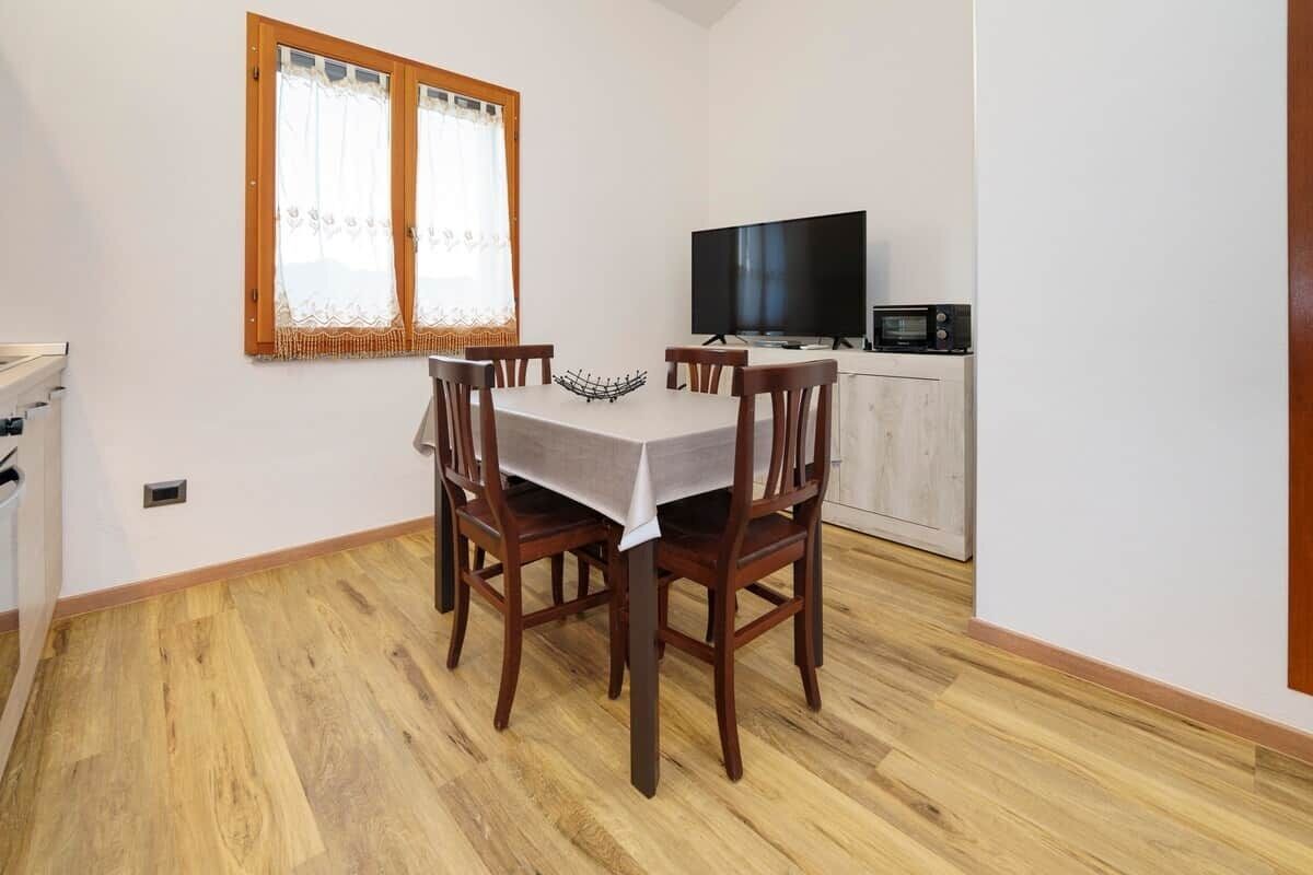 A dining area with a table and chairs, a television, and a microwave.