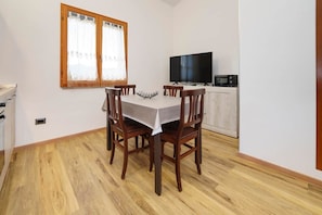 Un comedor con una mesa y sillas, un televisor y un microondas.