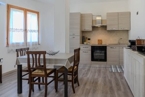 A modern kitchen with light wood cabinets, a built-in oven, and a dining area with a table and chairs. - Casa vacanze Sibilla appartamento Scirocco (Villa San Pietro)