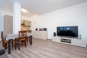 Ein modernes Wohnzimmer mit Fernseher, Holzesstisch und Stühlen.