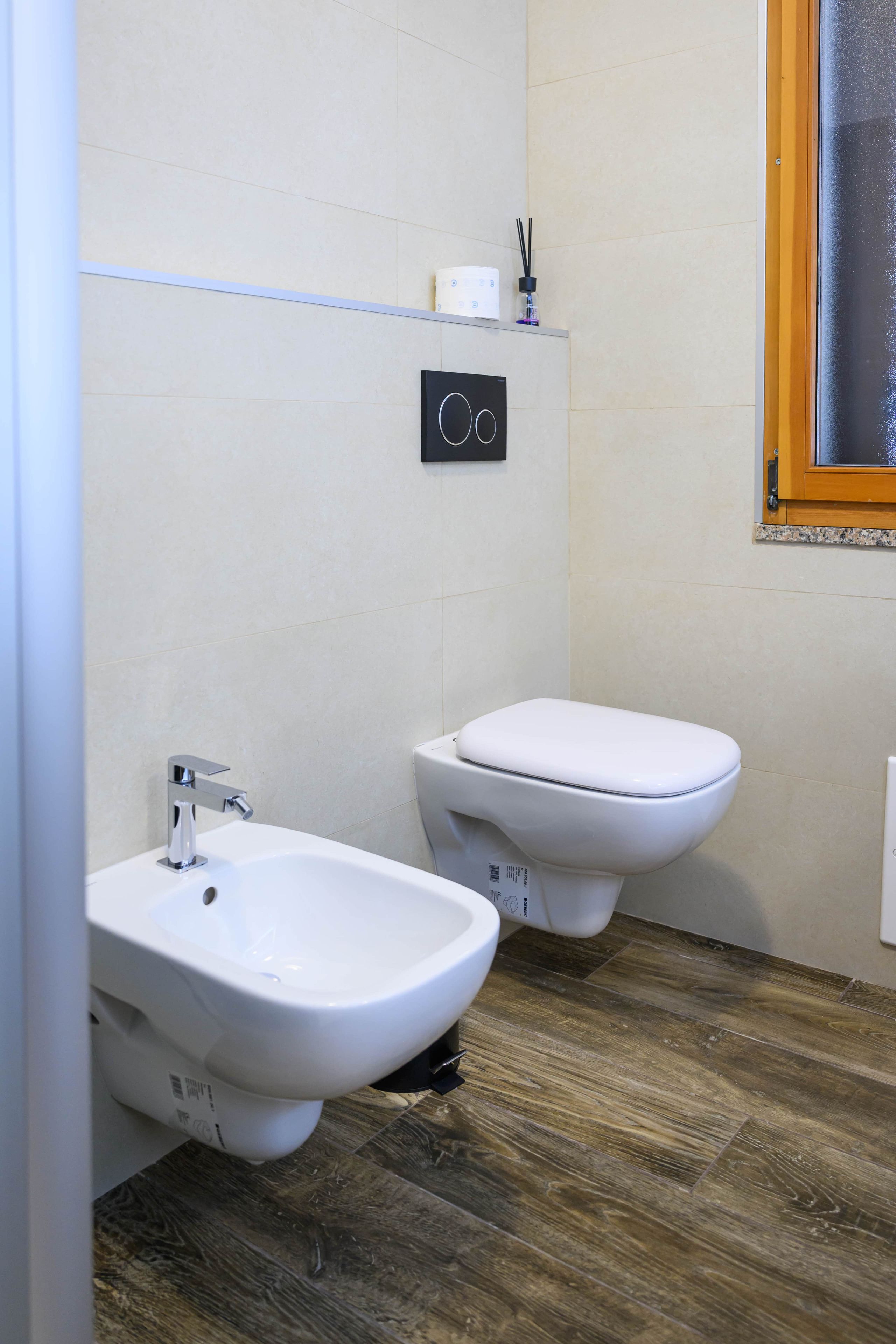 Un baño con dos inodoros, un bidé y un panel de control en la pared.